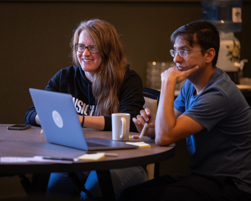 Two Insight M team members sitting at a table and looking engaged while listening to a presentation