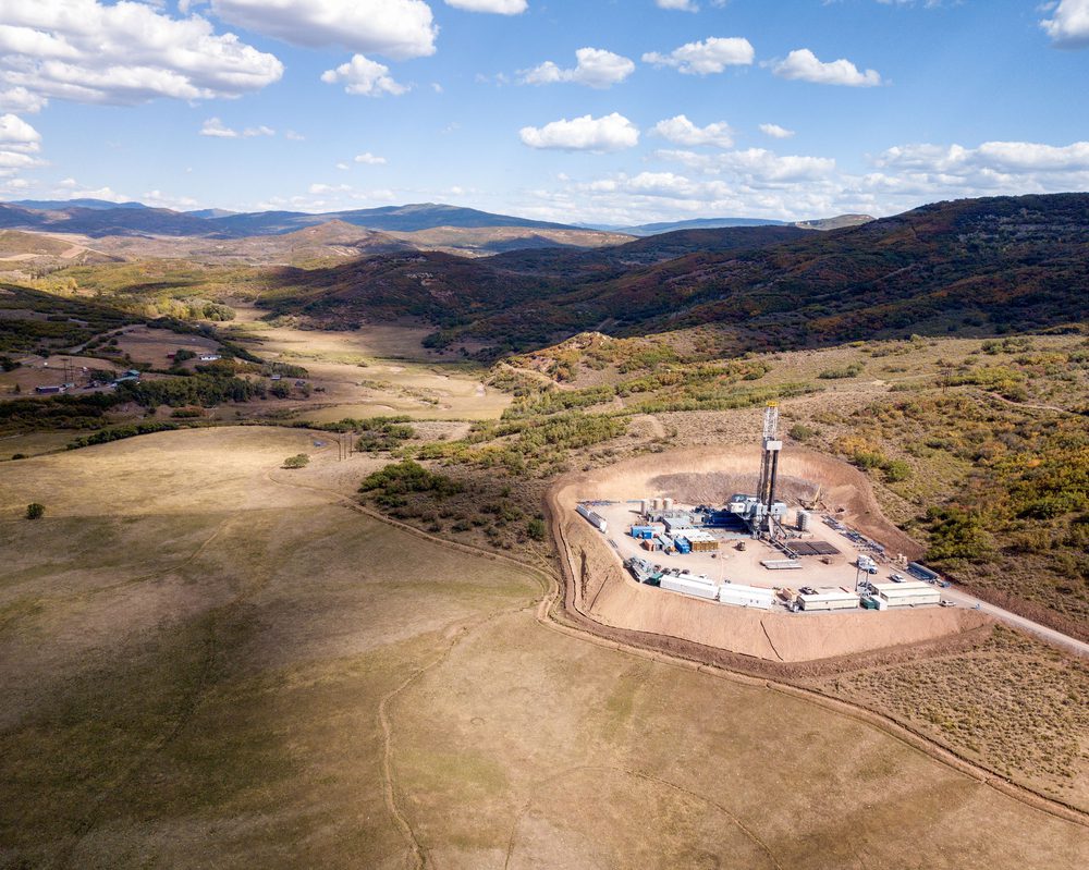 Wide angle view of an oil well in an arid, hilly landscape