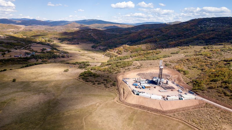 Wide angle view of an oil well in an arid, hilly landscape